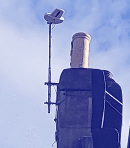 Aerial TV antenna and satellite dish installation on chimney for reliable signal reception in local homes.